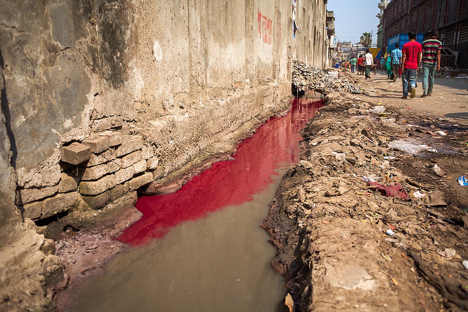 Waste water, red with dye, flows into an open drain in Hazaribagh, in western Dhaka.