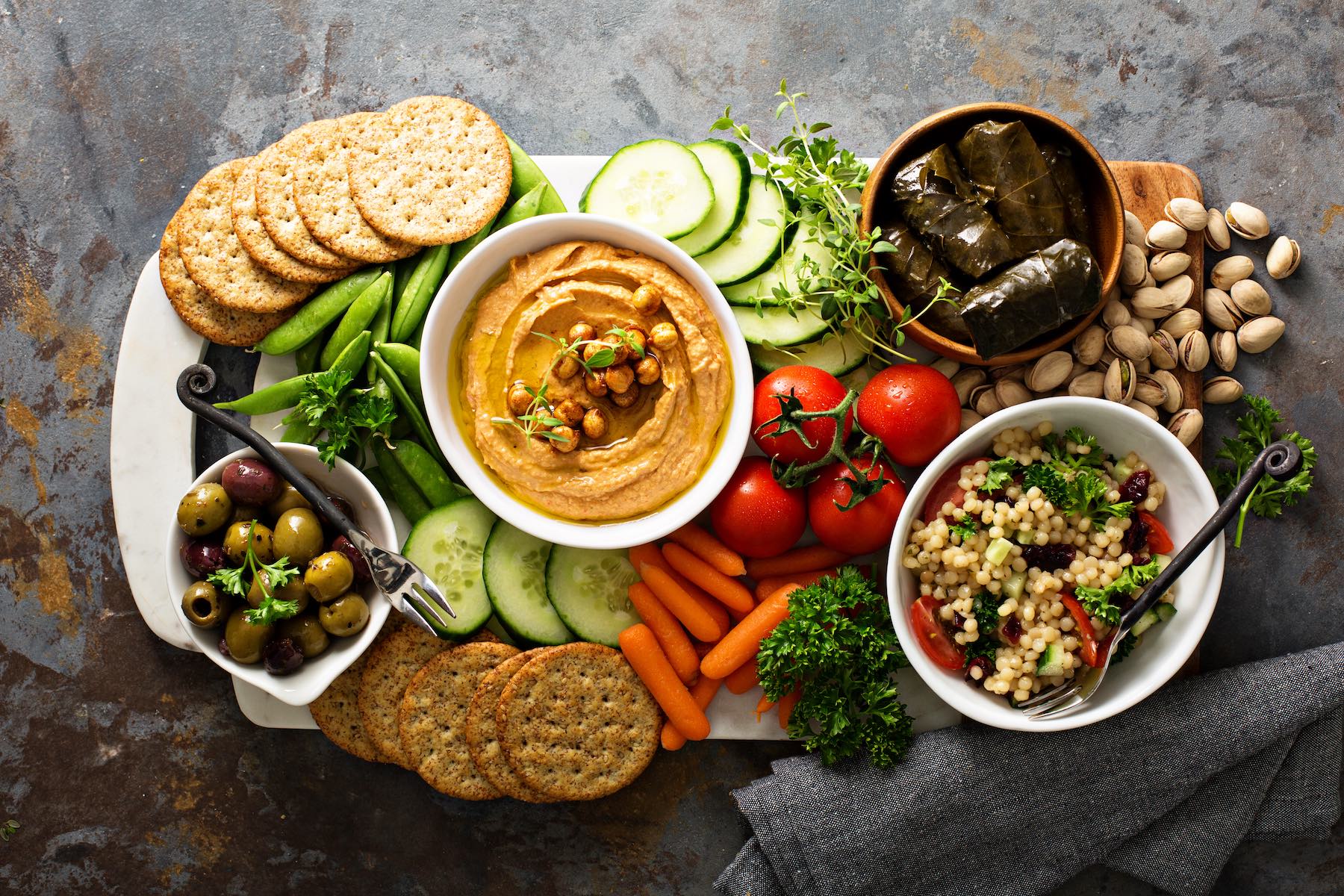 Hummus and fresh vegetables snack platter with grain salad and crackers
